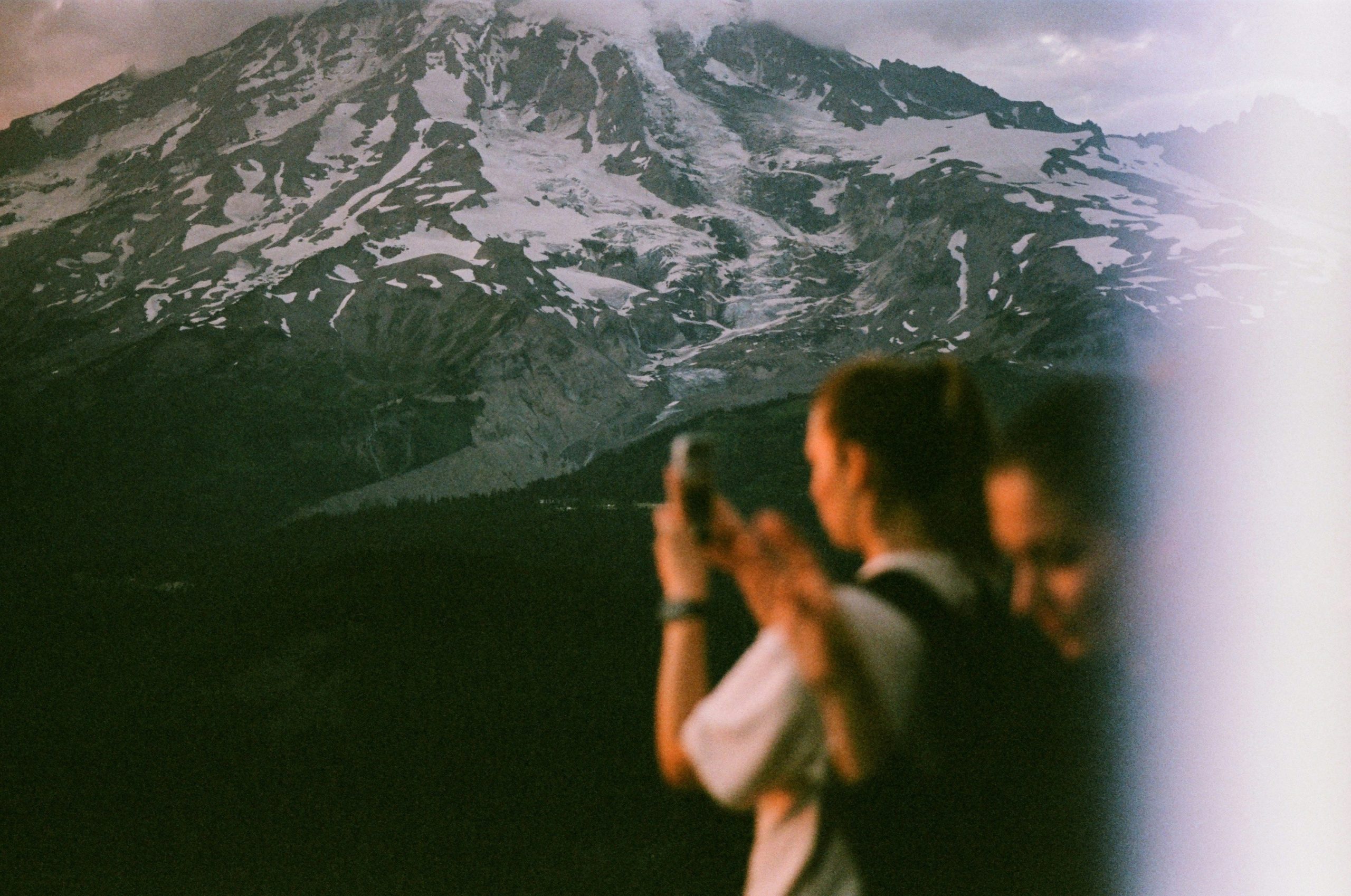 A hiker taking a scenic photo with a small camera