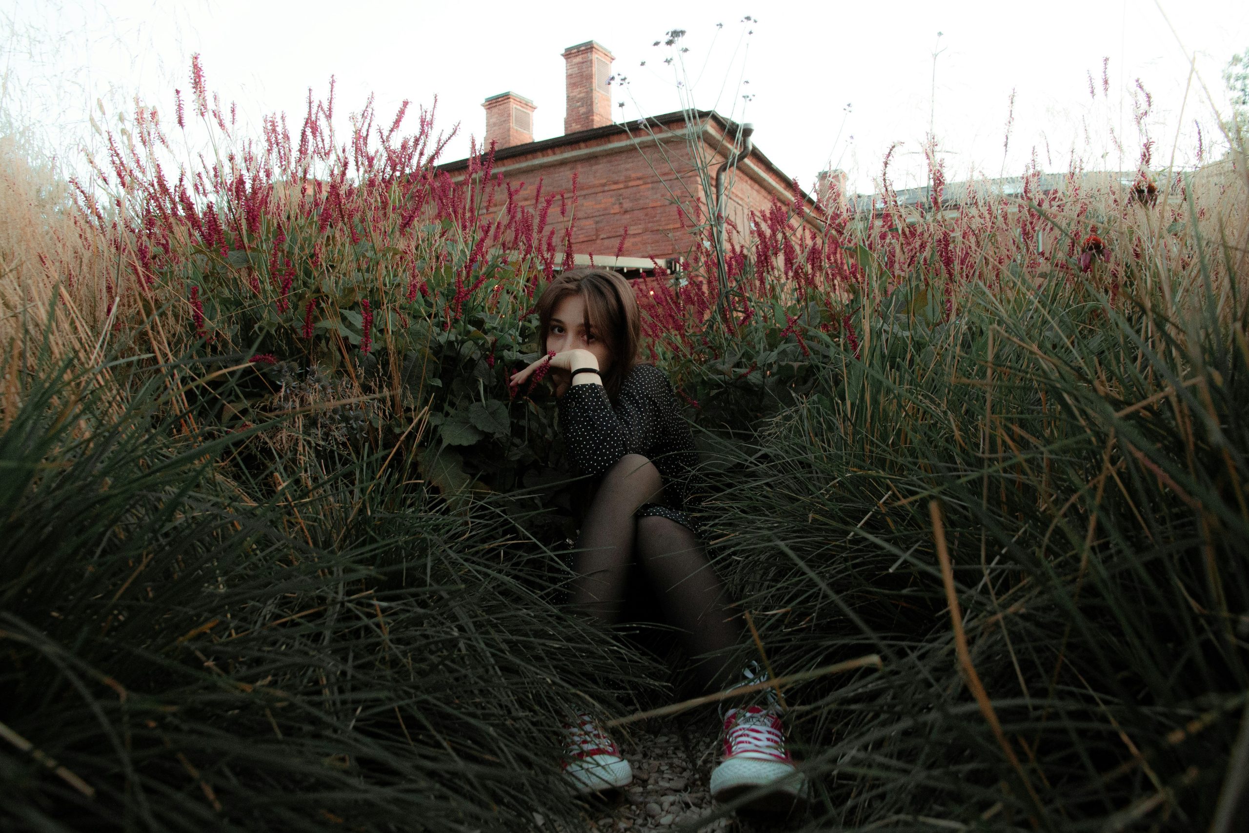 A photographer crouching behind bushes with a DSLR