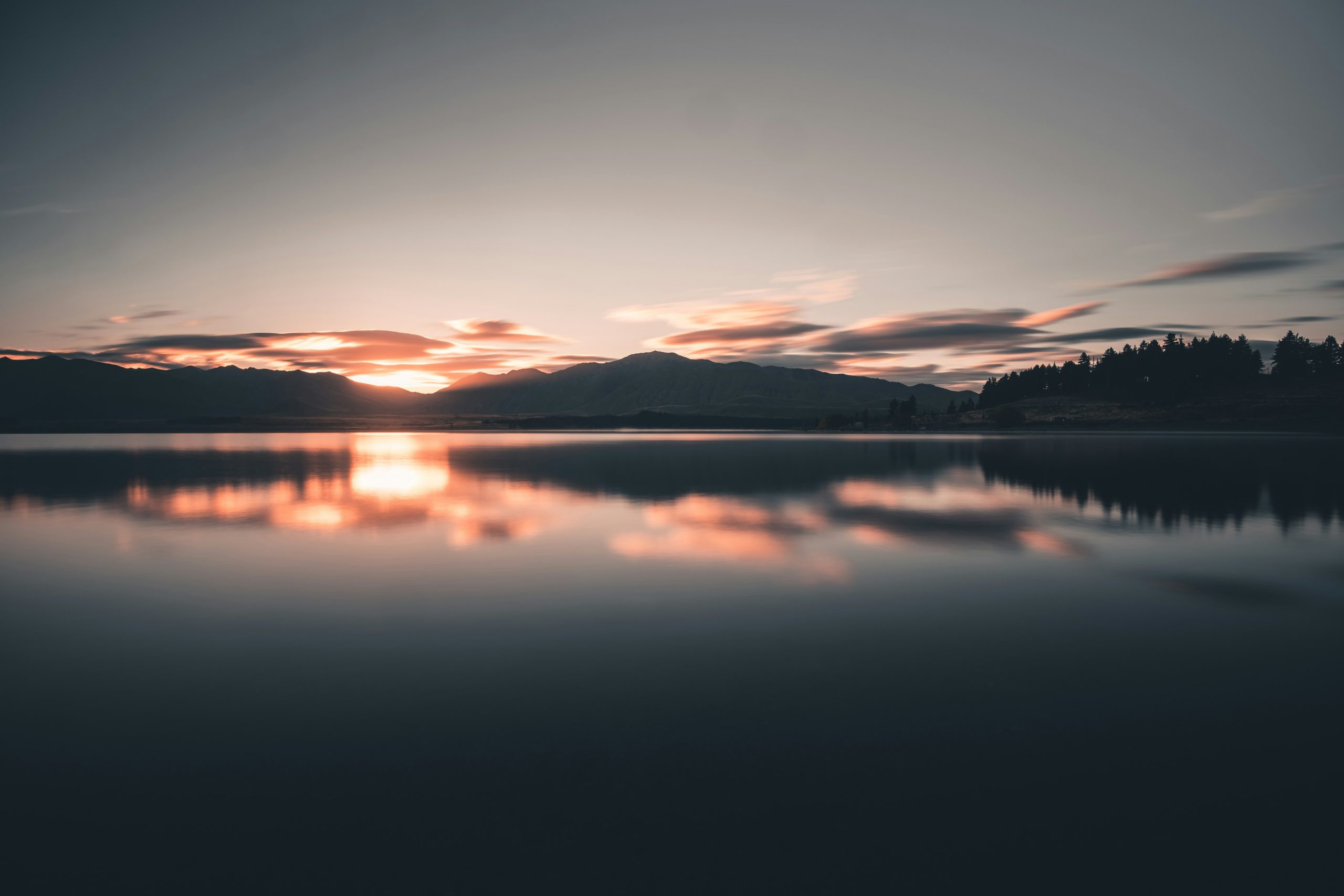 A serene lake reflecting towering peaks under golden-hour light
