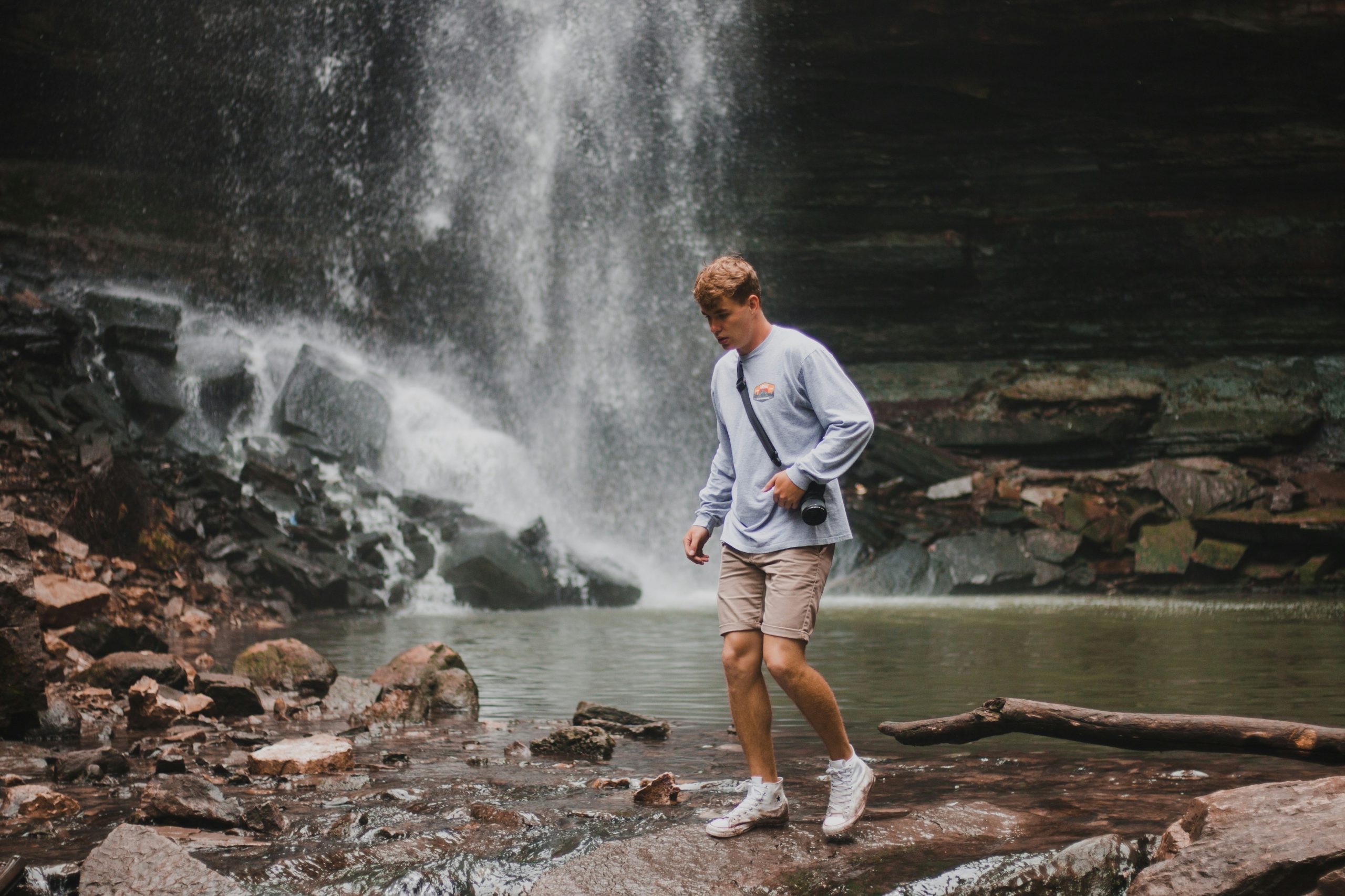 Hiker taking photos near a waterfall in heavy rain